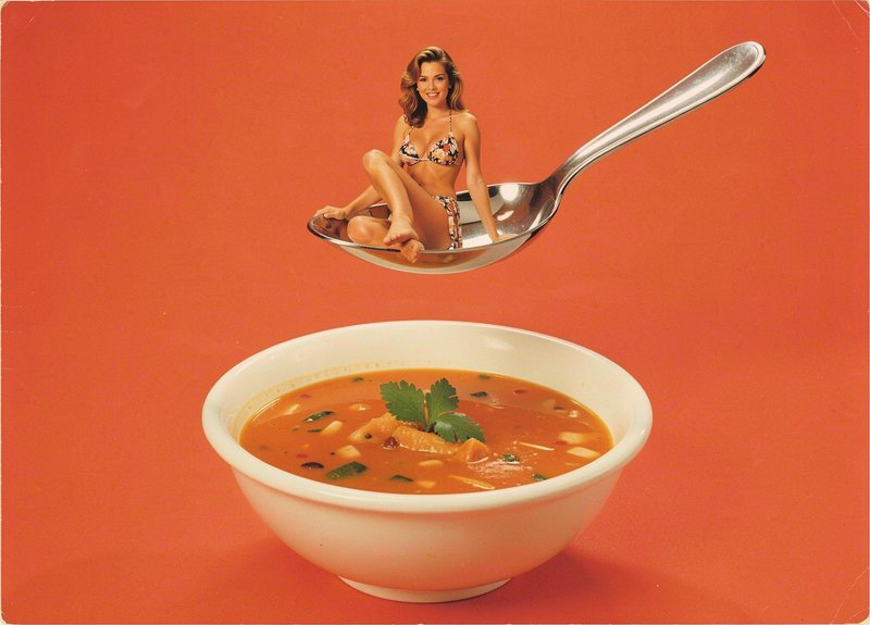 Smiling woman in a bikini sits on a giant metal spoon hovering above a bowl of garnished orange soup