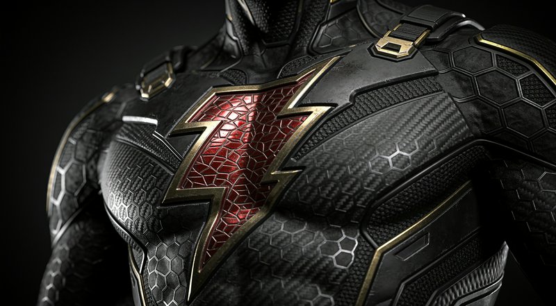 Close-up of a tactical black superhero suit with a red and gold lightning bolt chest emblem, against a dark studio