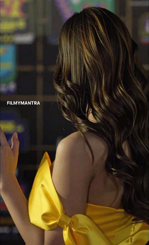 Woman in a yellow off-shoulder dress with a bow, seen from the back.