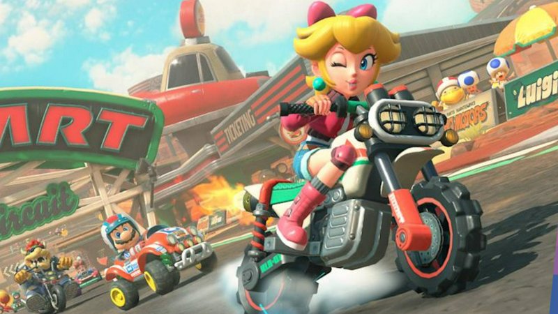 Princess Peach on a red-gray motorcycle racing on a bright, colorful track.