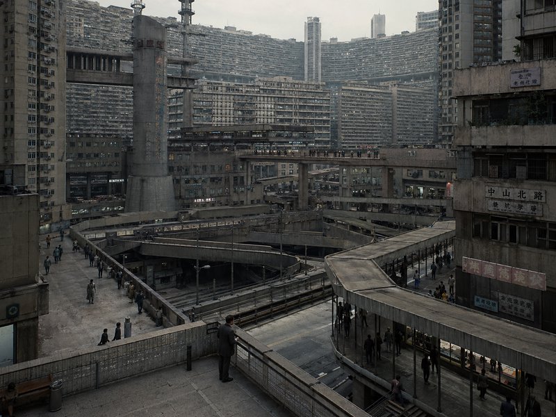 Dense brutalist megastructure with concrete blocks, elevated walkways, and a labyrinthine urban c...