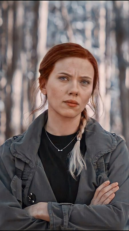 Portrait of a woman with red braided hair in a dark jacket in a forest backdrop