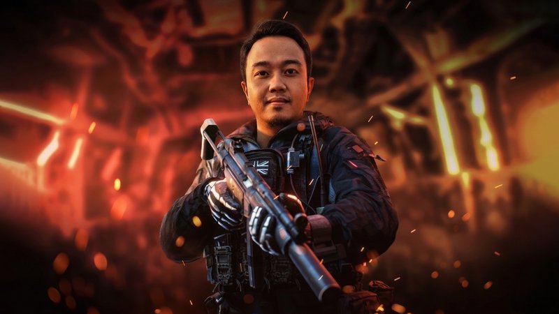 Male soldier in tactical gear holding a futuristic rifle amid a fiery, smoky battlefield.