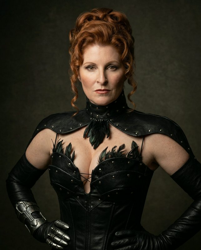 Woman in black leather armor with feather accents in a dramatic studio portrait