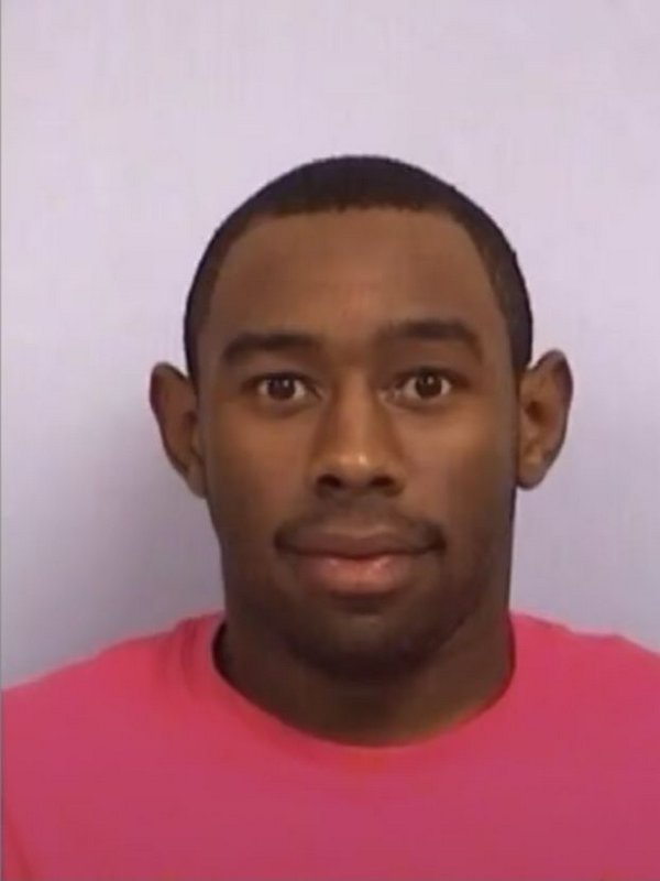 Portrait of a young man in a pink shirt against a light plain background.