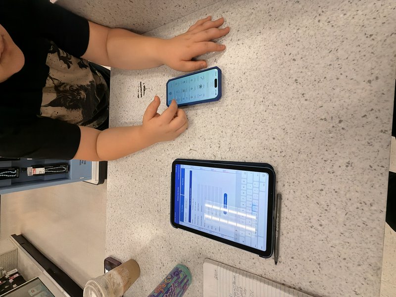 Overhead view of a retail worker touching a smartphone next to a POS tablet on a speckled store c...