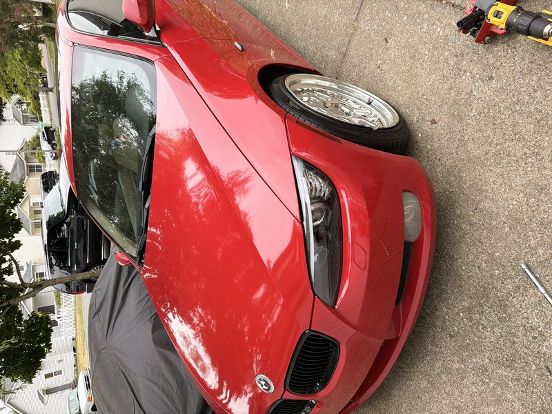 High angle close up of a glossy red BMW with custom chrome wheels on a residential concrete drive...