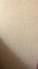 Close-up of beige woven fabric texture with subtle diagonal weave and soft shadows.
