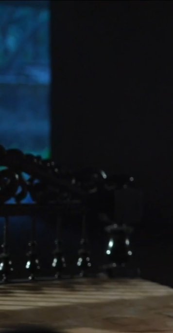 Dimly lit interior with a blue glow on the left and decorative railing in the foreground.