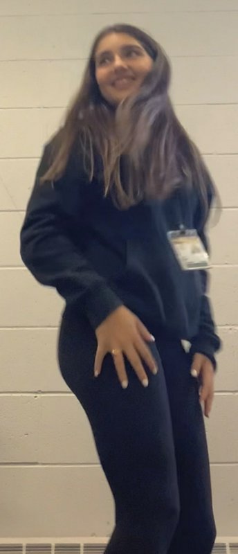 Blurred candid shot of a smiling young woman with long highlighted hair, wearing a black hoodie, ...
