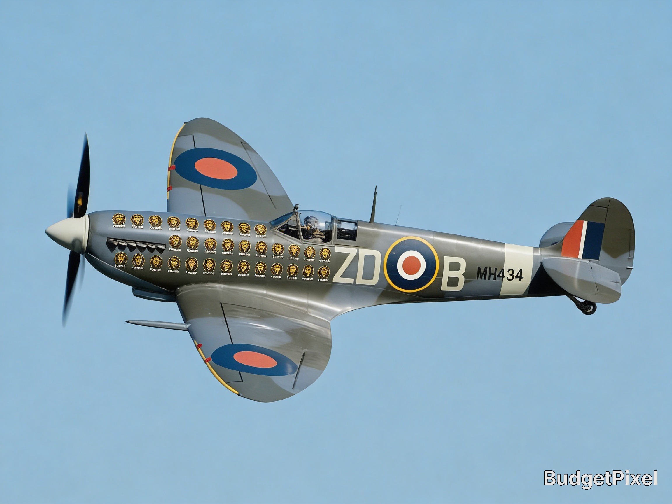 Vintage RAF Spitfire fighter in flight with portrait decals along the fuselage and roundels.