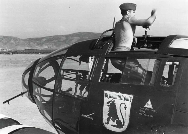 Vintage pilot in open cockpit of WWII-era bomber saluting with desert backdrop