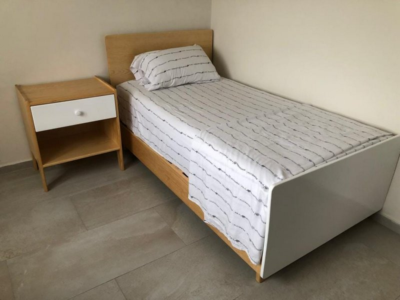 Single wooden-framed twin bed with striped bedding and matching nightstand.