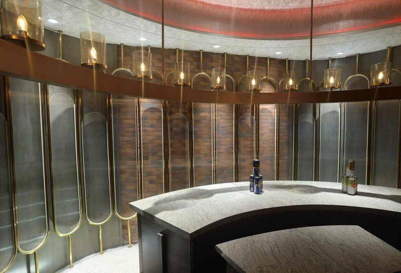 Circular marble bar with gold-trimmed glass walls and warm ambient lighting.