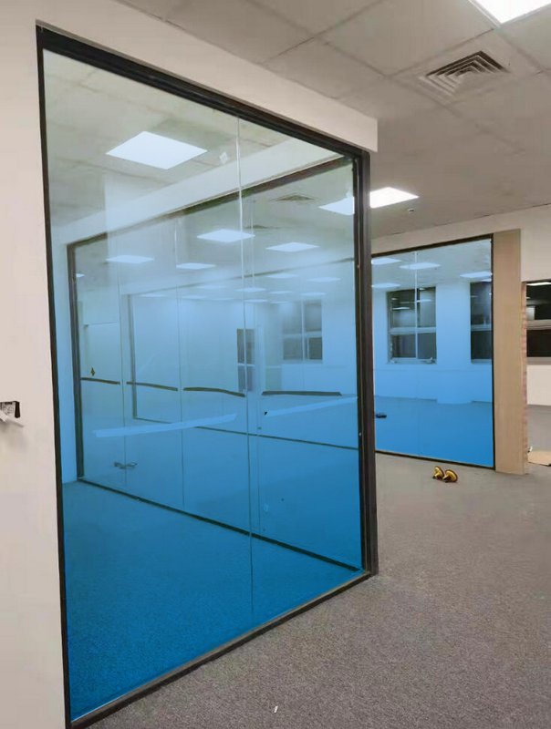Modern office interior with blue-tinted glass partition walls and hallway.