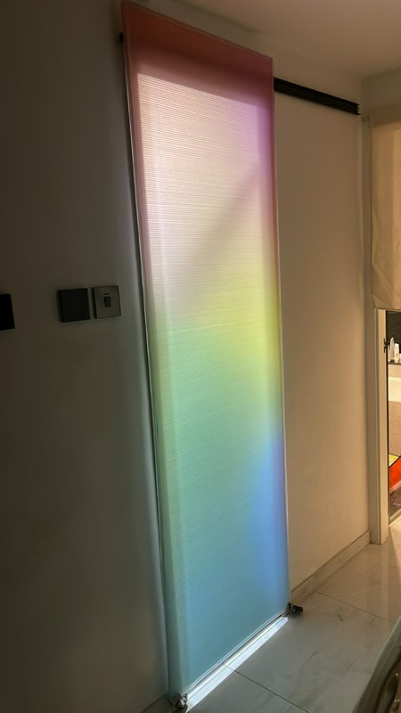 Frosted vertical glass panel with a rainbow gradient light in a modern interior.