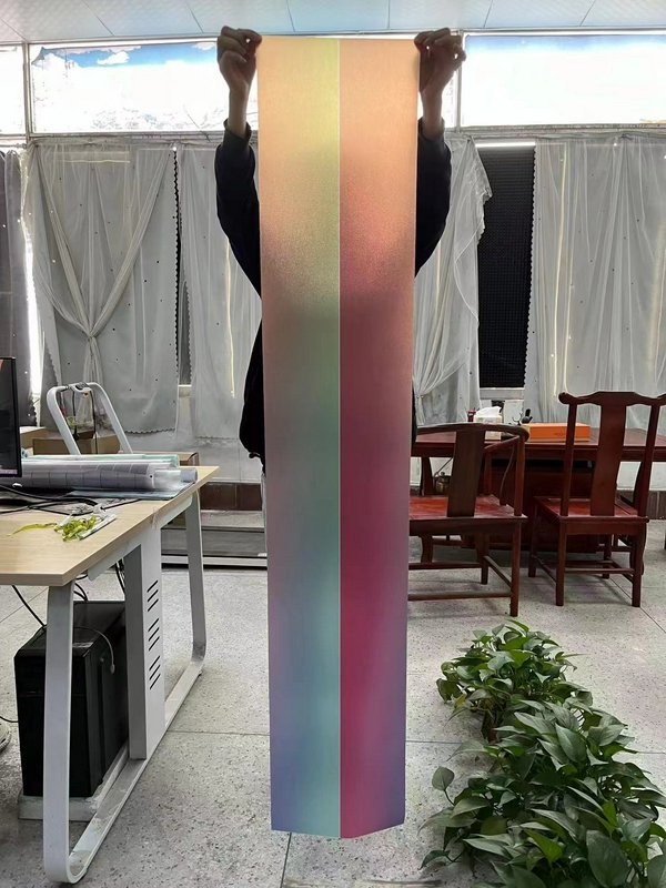 Long vertical gradient color swatch held up in an office/studio setting