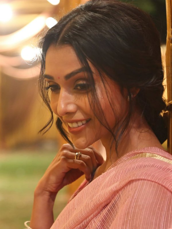 Indian woman with a warm smile in a pink saree, soft evening lighting.