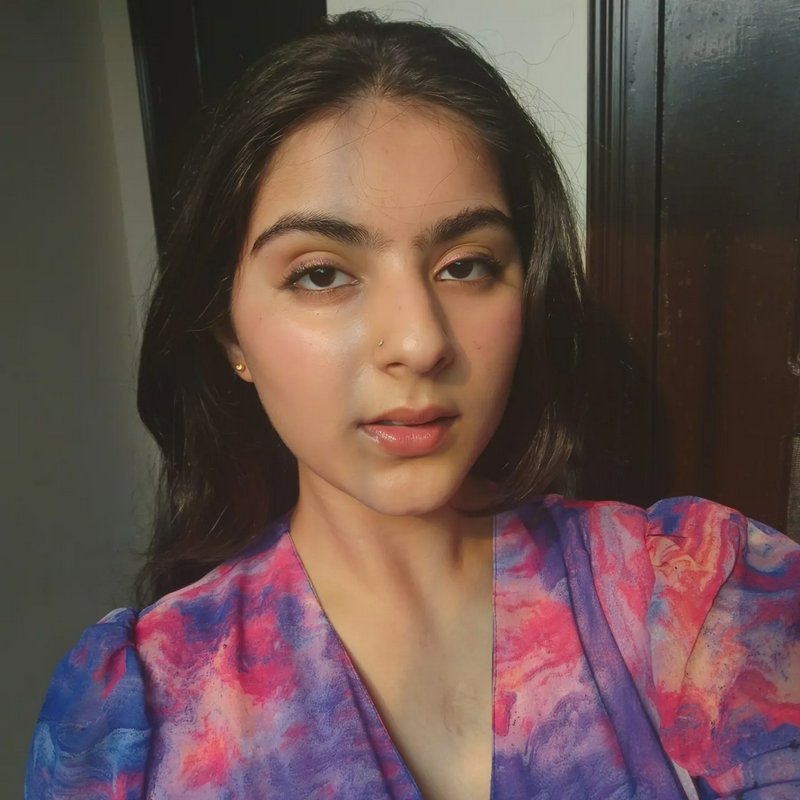 Close-up portrait of a young woman with dark hair wearing a pink-purple tie-dye blouse.