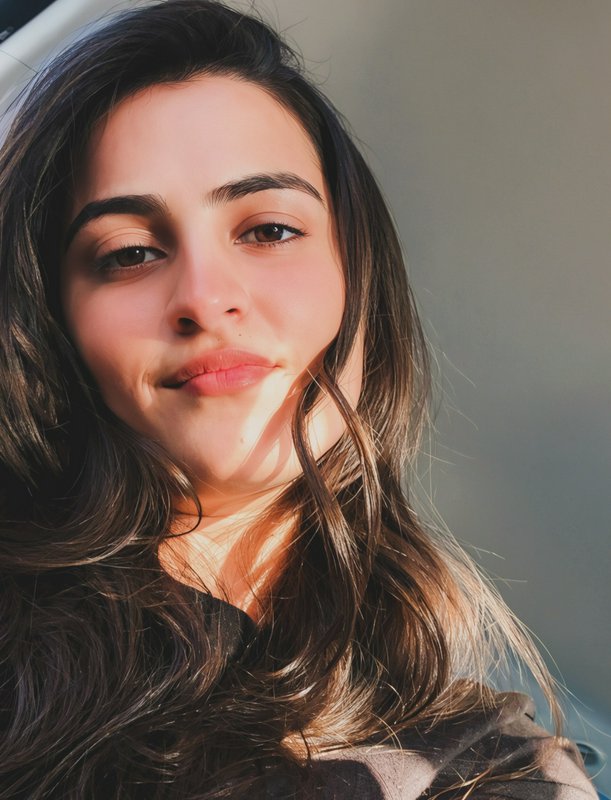 Close-up portrait of a young woman with long dark hair bathed in natural light.