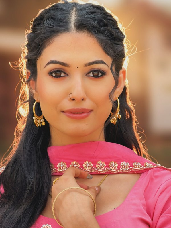 Portrait of a woman in pink traditional attire with gold jewelry and braided hairstyle