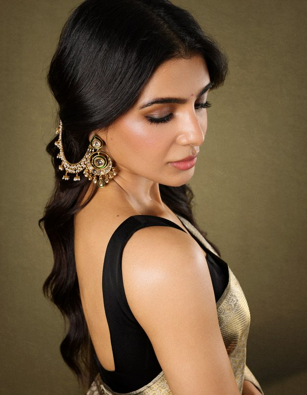 "Actress Samantha Ruth Prabhu wears an ornate Kundan ear chain with a golden saree, looking softl...