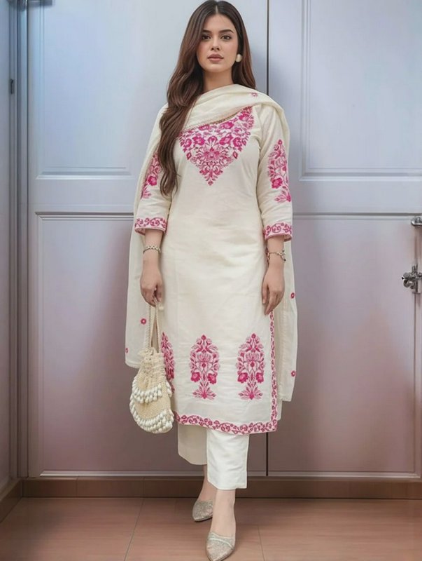 Woman modeling cream Pakistani salwar kameez with bright pink floral embroidery, holding a woven ...