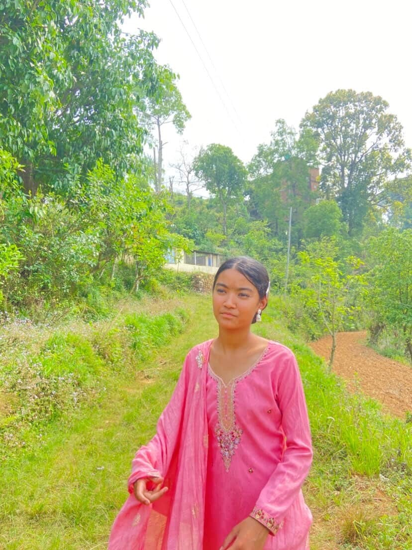 Young girl in pink traditional dress walking along a rural green path