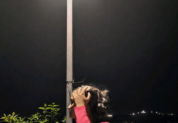 [Side profile of a woman running her hand through her hair next to a street lamp pole on a dark quiet night]