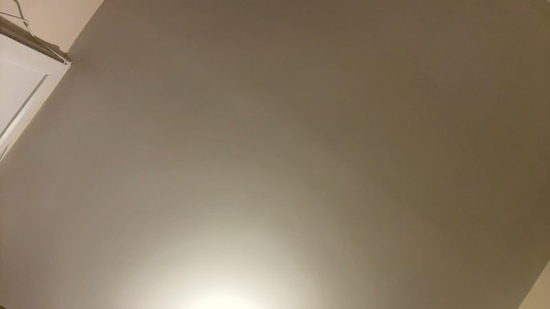 Interior ceiling with a warm recessed light, gray walls, and a doorway corner.