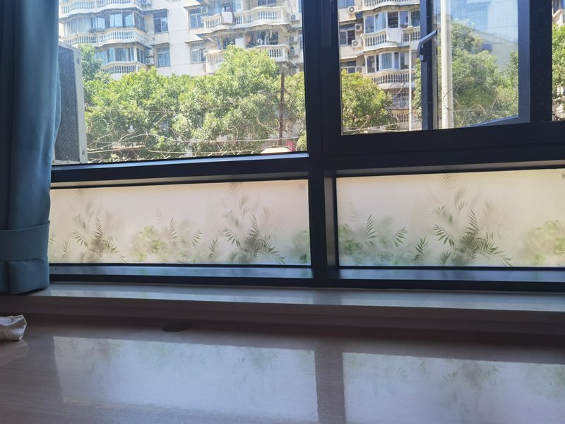 Indoor window view with frosted glass panels, blue curtains, and a cityscape outside