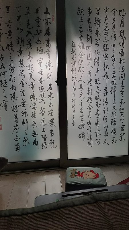 Two hanging Chinese calligraphy panels with flowing black ink characters on white paper by a window.