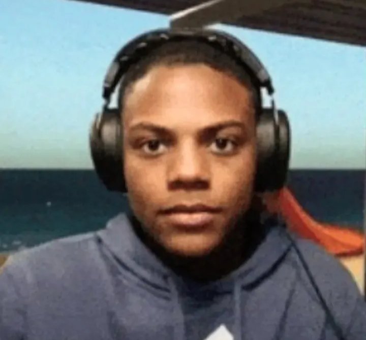 Young person wearing large black over-ear headphones and a dark hoodie, facing the camera.