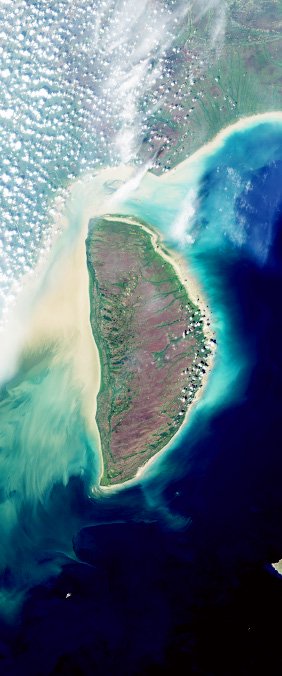 Aerial view of a narrow tropical island with turquoise lagoons and white-sand shoreline.