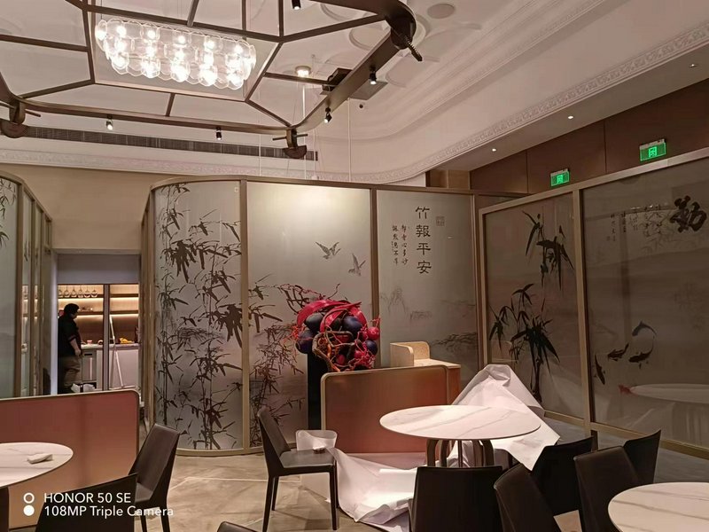 Elegant restaurant interior with bamboo screen panels, round tables, and a red decorative centerp...