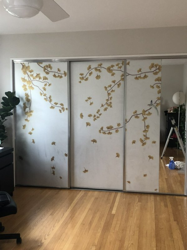 Sliding closet doors with a gold leaf vine pattern in a modern bedroom.