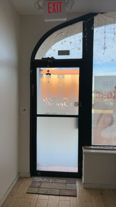 Interior arched glass door with frosted panels, red EXIT sign, and string lights in a small shop.