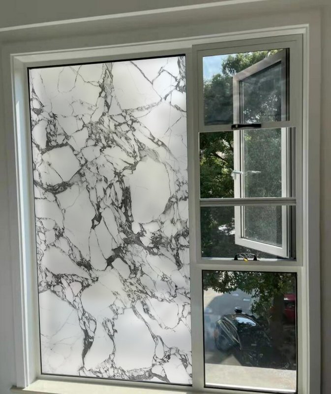 Large white marble-pattern wall panel beside an open window with bold gray veining.