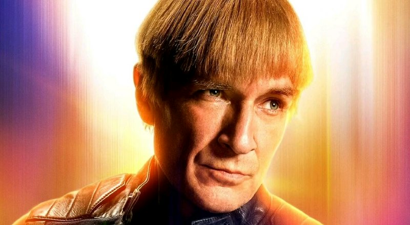 Close-up portrait of a man with blonde hair in a futuristic, colorful glow.
