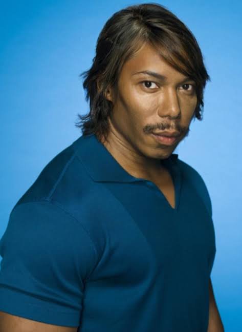 Man wearing a blue polo shirt posed against a blue studio background.