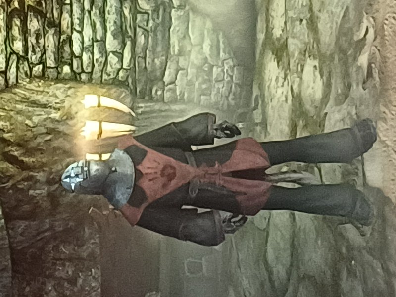 Two armored figures in red and black costumes stand in a rocky dungeon setting with masked faces.