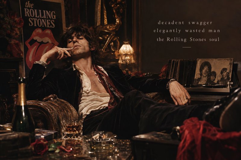 70s rockstar in a velvet suit lounges decadently surrounded by Rolling Stones memorabilia, vinyl records, and drinks.