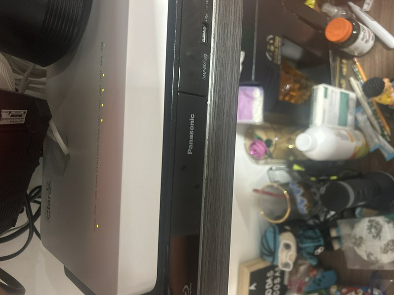 Close-up of a Panasonic electronic device with LED indicators on a desk.