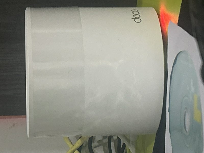 Close-up of a white paper/label roll mounted in a printer with cables nearby and a partial blue c...