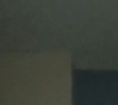 Dim interior corner with dark shadows between a pale wall and ceiling.