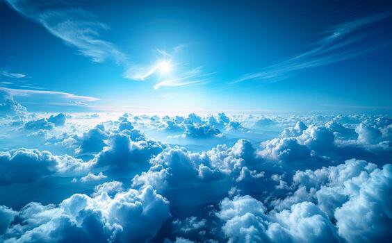 Aerial view of bright sun over a vast sea of fluffy blue clouds in a clear sky