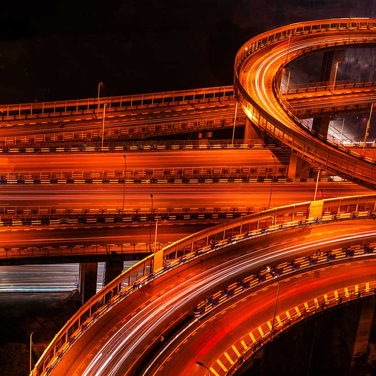 Nighttime highway interchange with curving elevated ramps and orange light trails
