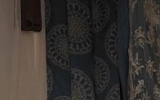 Blue patterned curtains with circular mandala-like designs hanging beside a beige wall.