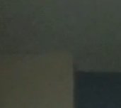 Dim interior corner with dark shadows between a pale wall and ceiling.