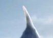 Dark fin-like silhouette rising against a clear blue sky.